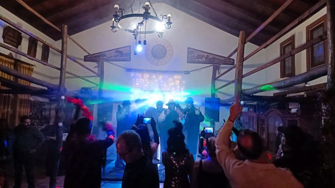 Concierto en un local con luces brillantes y una multitud disfrutando.